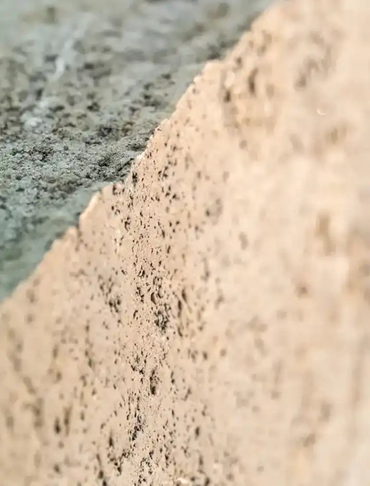 Detall de pedra natural de textura porosa i tonalitats beix i crema, tall en diagonal, Construccions Ramilo