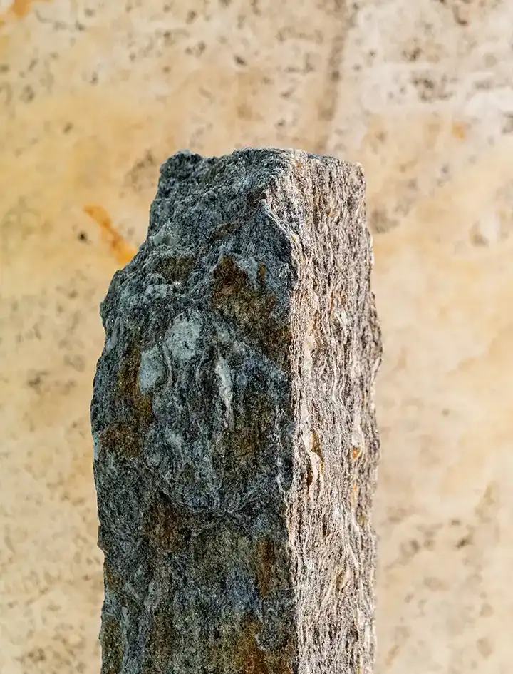 Bloc de pedra natural fosca de tons verdosos i grisos sobre fons de pedra clara, Construccions Ramilo