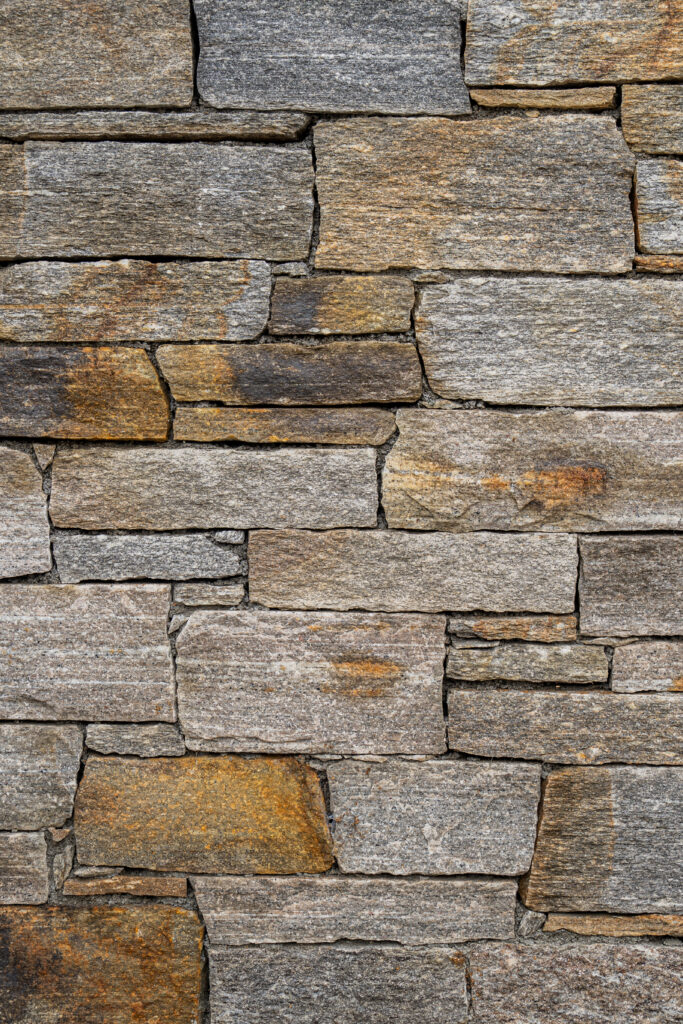 Mur de pedra artesana natural Barreta Gneiss amb peces estretes i allargades de disposició horitzontal, tons grisos amb matisos beix i ocres, textura estriada i vetes fines de gneis, per a façanes sòbries i ordenades — Construccions Ramilo