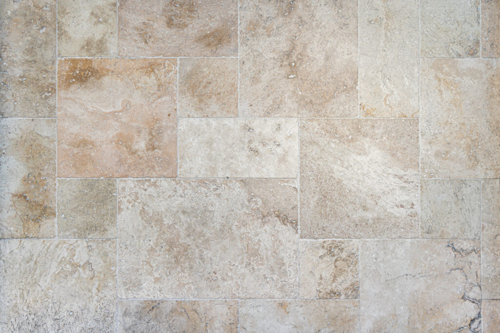 Lama de pedra natural Travertí amb peces allargades de tall precís, tonalitats beix, crema i sorra, textura porosa i vetes naturals, per a façanes i murs d'estètica càlida i refinada — Construccions Ramilo