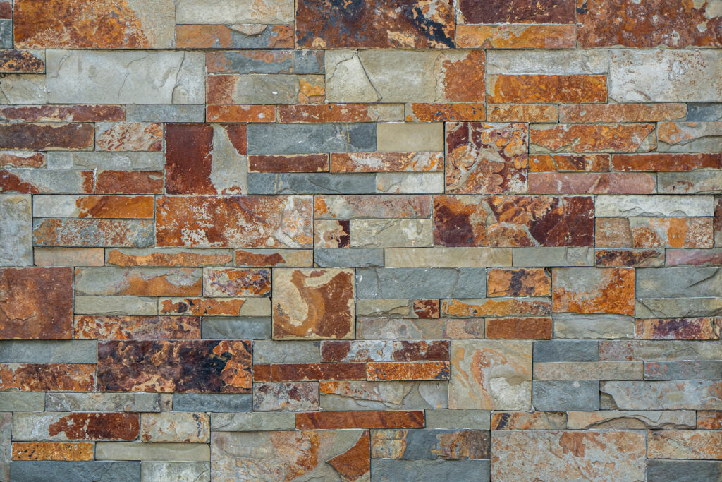 Panell de pedra natural Multicolor Fi amb peces fines i allargades de disposició irregular, gamma cromàtica d'ocres, rovell, terracota, grisos i beixos i textura natural, per a façanes i murs d'accent — Construccions Ramilo