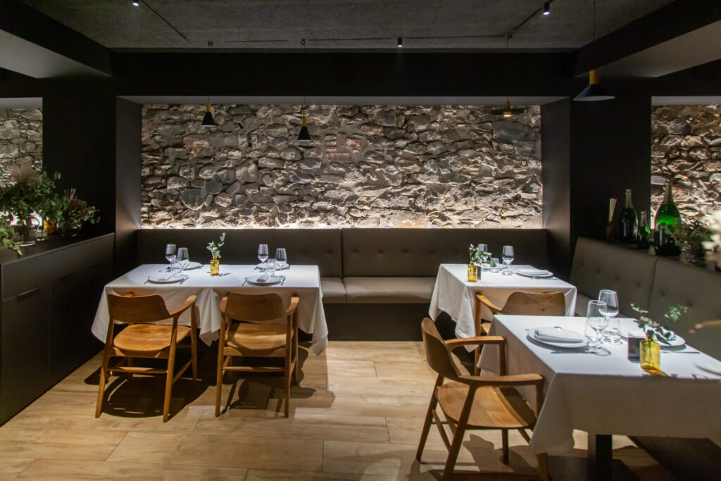 Detall de la paret de pedra natural de Borda amb il·luminació cuidada al Restaurant Can Manel, Construccions Ramilo