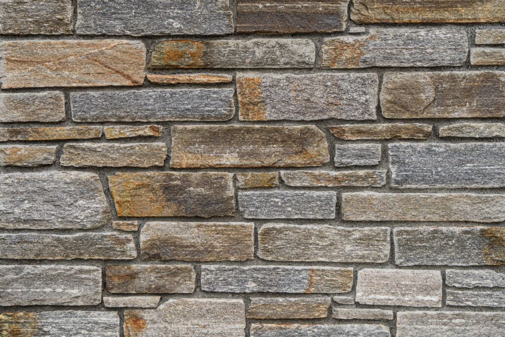 Mur de pedra artesana natural Barreta Gneiss amb peces estretes i allargades de disposició horitzontal, tons grisos amb matisos beix i ocres, textura estriada i vetes fines de gneis, per a façanes sòbries i ordenades — Construccions Ramilo
