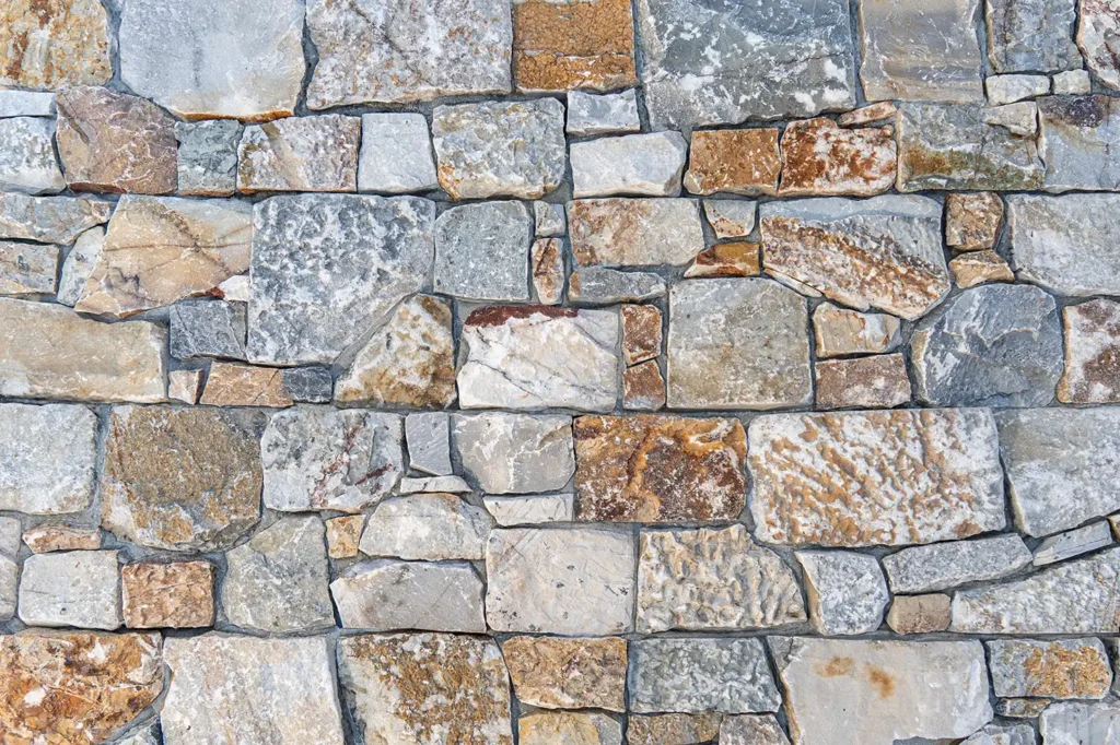 Panell de pedra natural Summer Stone amb peces allargades de tonalitats càlides, ocres i daurats, textura natural i acabat lluminós, per a façanes i revestiments, Construccions Ramilo